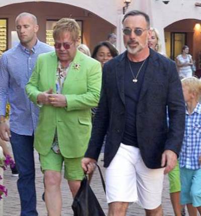 إلتون جون يرتدي ملابسه الغريبة ليتسوق مع زوجه